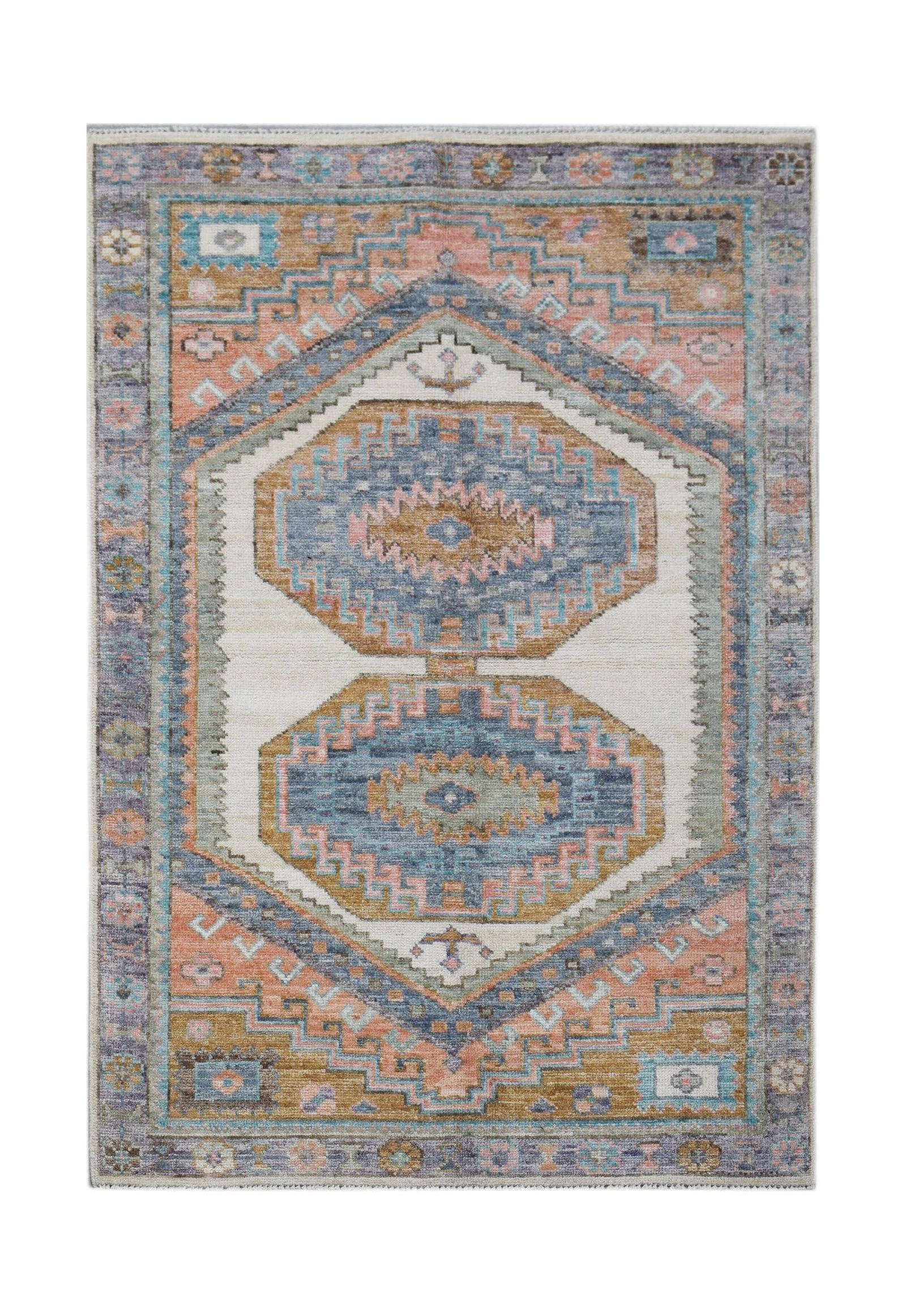 A handwoven transitional Oushak rug featuring geometric medallions in blue, pink, and gold tones.