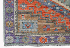 A handwoven wool Oushak rug featuring a geometric pattern in orange, blue, and purple tones.