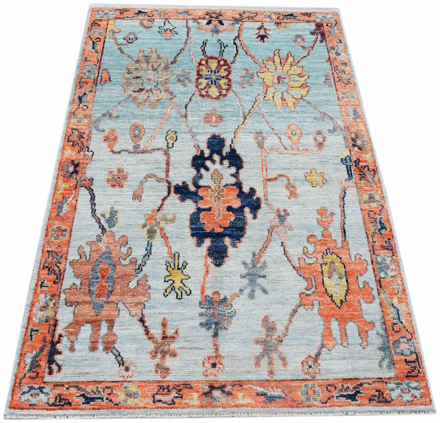 A handwoven transitional Oushak rug featuring a floral pattern in blue, orange, and yellow tones.