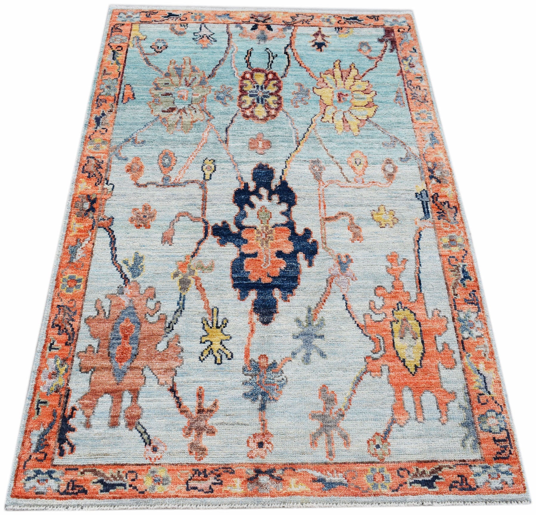 A handwoven transitional Oushak rug featuring a floral pattern in blue, orange, and yellow tones.