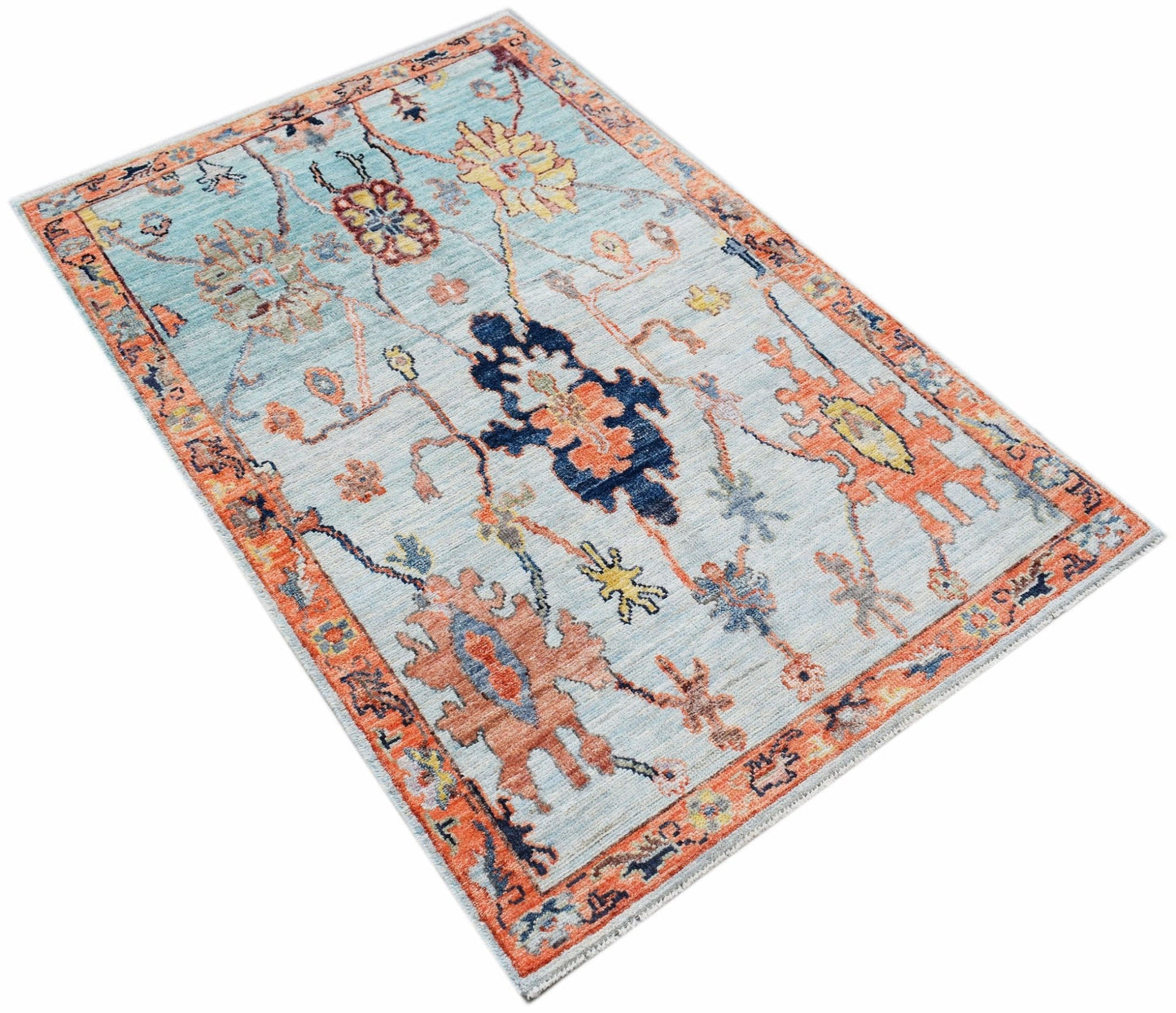 A handwoven transitional Oushak rug featuring a floral pattern in blue, orange, and cream tones.