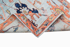 A handwoven transitional Oushak rug featuring a floral pattern in blue, orange, and yellow tones.
