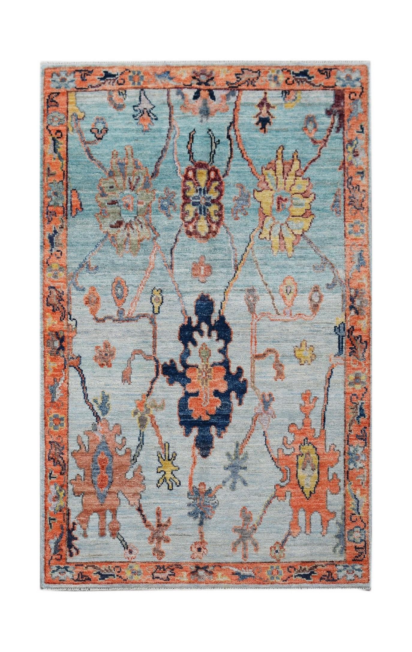 A handwoven transitional Oushak rug featuring a floral pattern in blue, orange, and yellow tones.