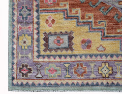 A handwoven transitional Oushak rug featuring a geometric pattern in shades of purple, yellow, and red.