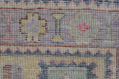 A close-up of a handwoven Oushak rug featuring geometric patterns in muted pastel tones.