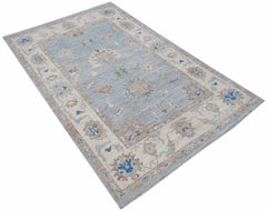 A handwoven transitional Oushak rug featuring a floral pattern in blue, beige, and grey tones.