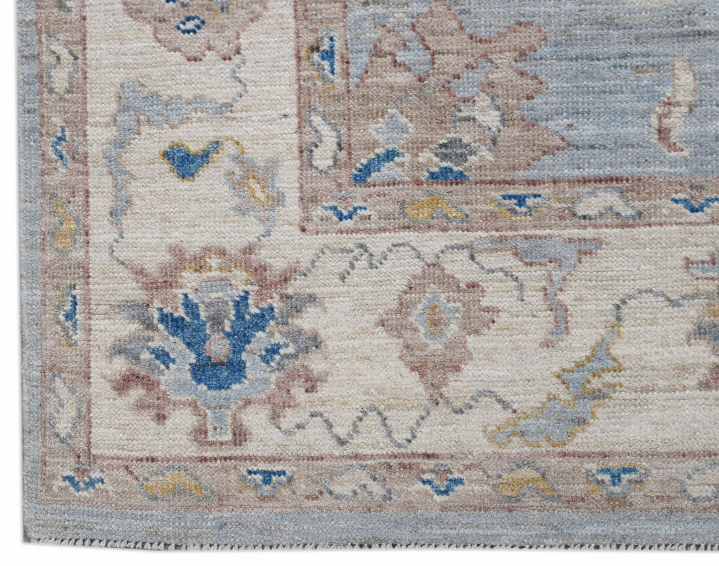 A handwoven transitional Oushak rug featuring a floral pattern in blue, beige, and muted tones.