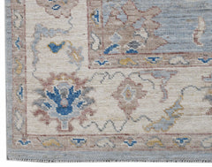 A handwoven transitional Oushak rug featuring a floral pattern in blue, beige, and muted tones.