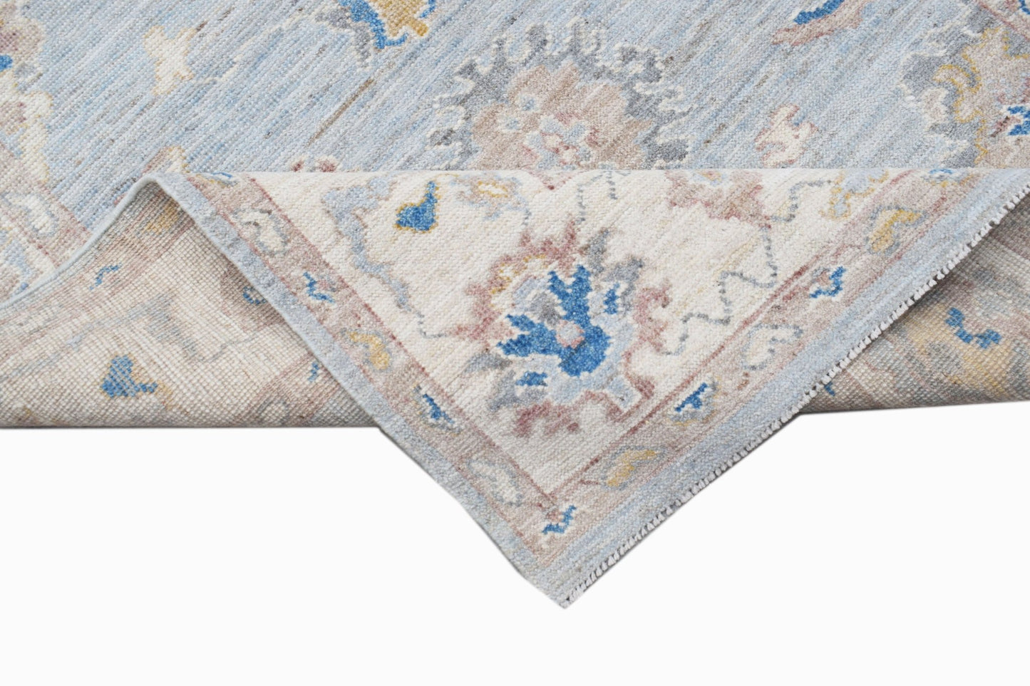 A handwoven transitional Oushak rug with a floral pattern in blue, beige, and grey tones.