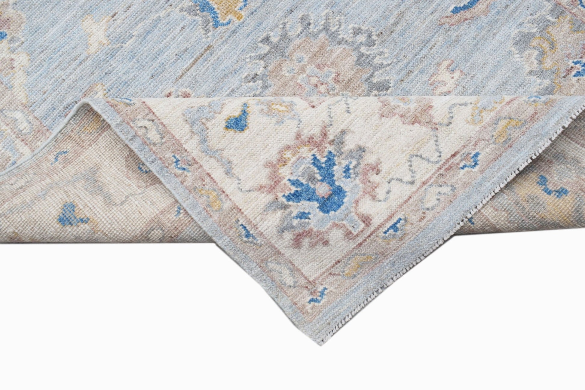 A handwoven transitional Oushak rug with a floral pattern in blue, beige, and grey tones.