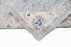 A handwoven transitional Oushak rug with a floral pattern in blue, beige, and grey tones.