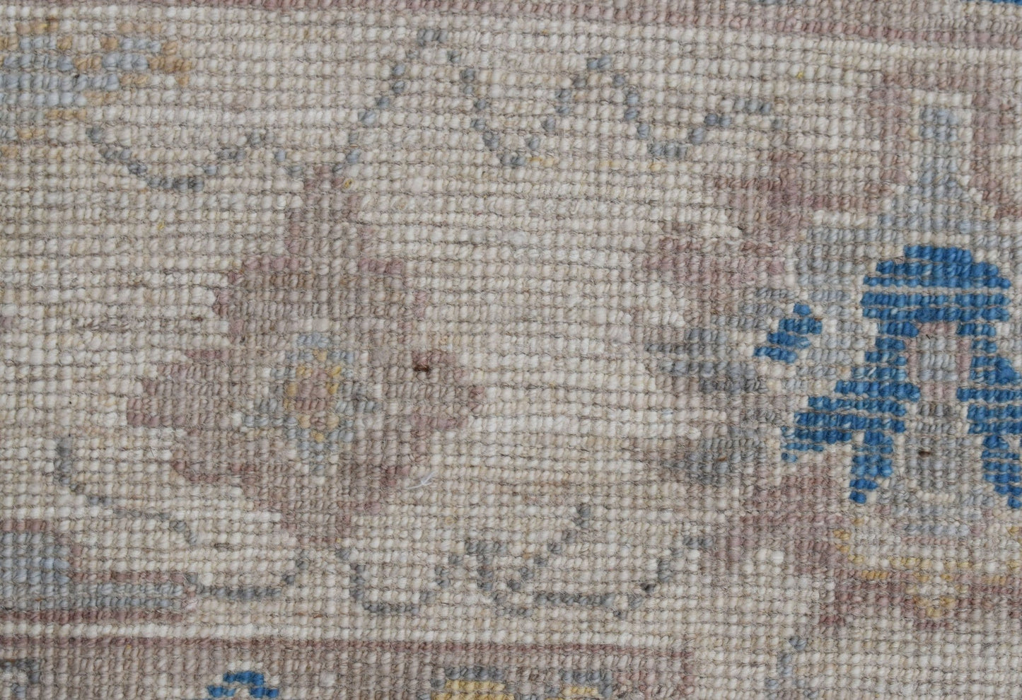 A close-up of a handwoven transitional Oushak rug featuring a floral pattern in muted tones.