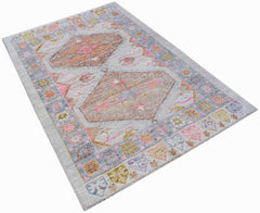 A handwoven transitional Oushak rug featuring a light grey field with pink and tan geometric motifs.