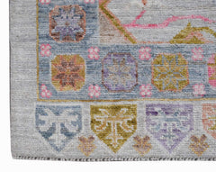 A handwoven transitional Oushak rug featuring a geometric floral pattern in soft pastel tones.