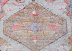 A transitional Oushak rug featuring a central floral medallion in soft pink, blue, and tan tones.
