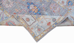 A handwoven transitional Oushak rug featuring a floral pattern in blue, grey, and muted tones.