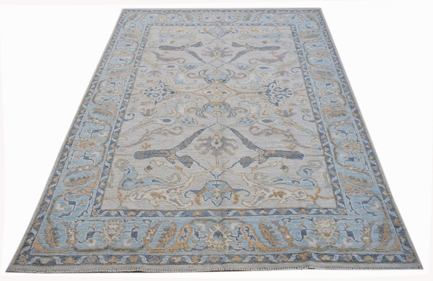 A handwoven transitional Oushak rug featuring a light blue and beige floral pattern.