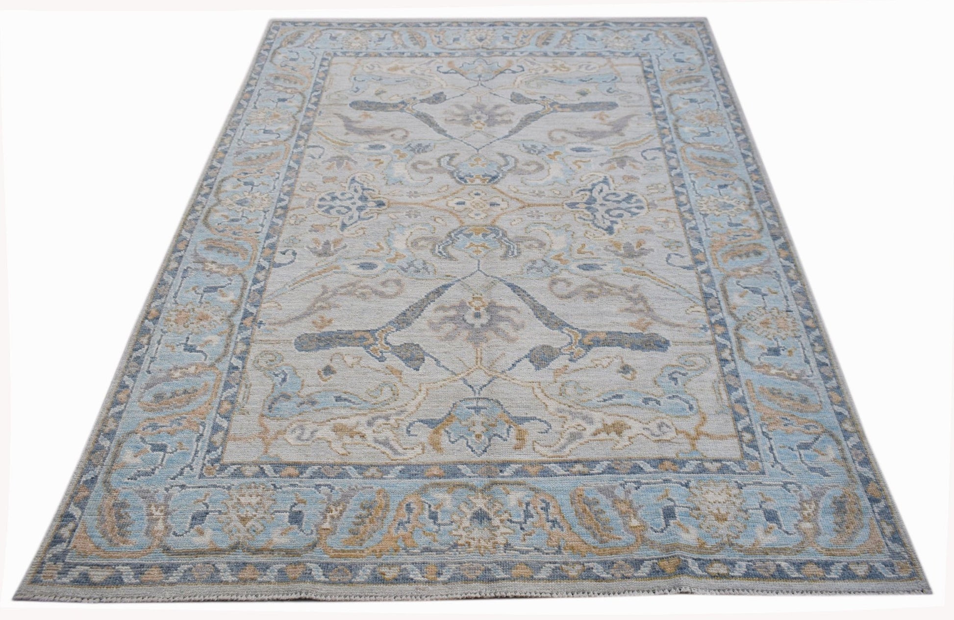 A handwoven transitional Oushak rug featuring a light blue and beige floral pattern.