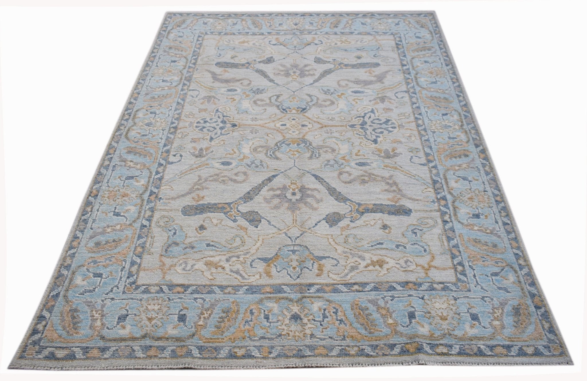 A handwoven transitional Oushak rug featuring a light blue and beige floral pattern.