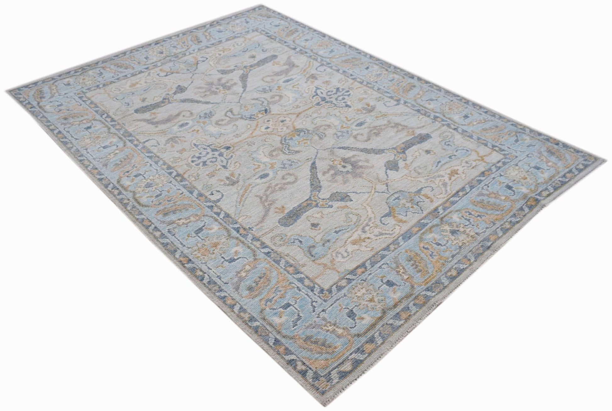A handwoven transitional Oushak rug featuring a floral pattern in soft blue and beige tones.
