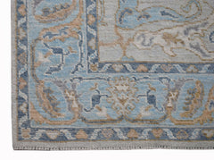 A handwoven transitional Oushak rug featuring a blue and beige floral pattern on a light background.