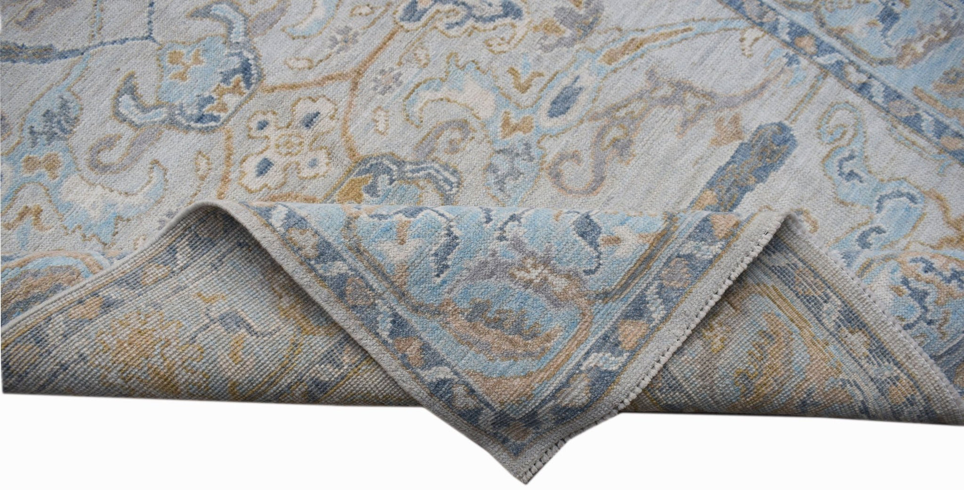 A handwoven transitional Oushak rug featuring a blue and beige floral pattern on a light background.