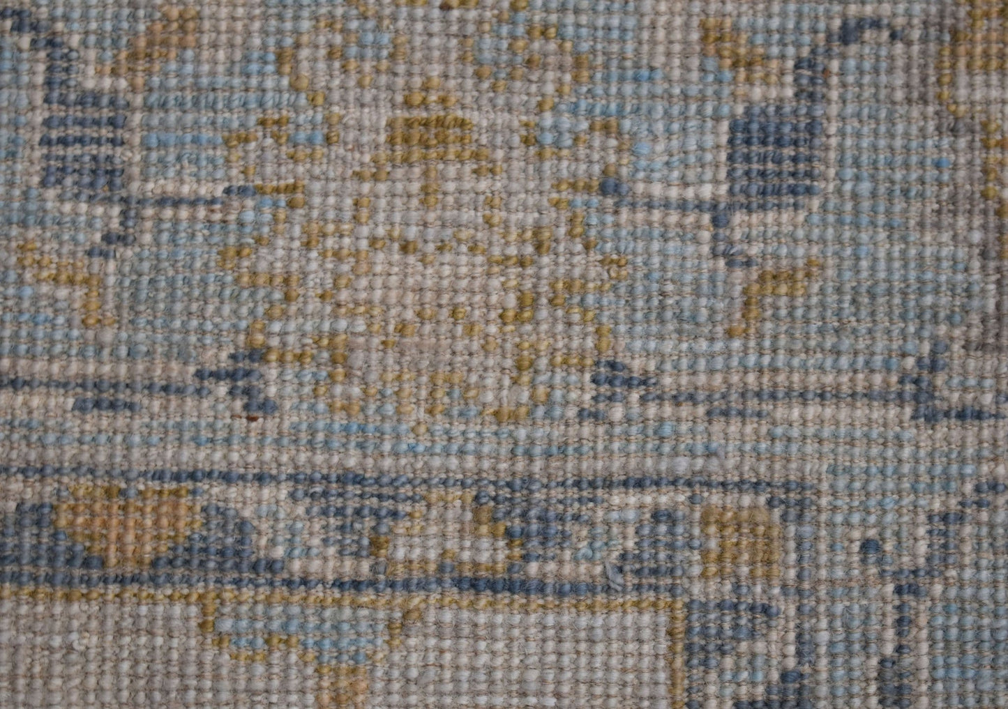 A handwoven transitional Oushak rug featuring a floral pattern in blue, yellow, and beige tones.