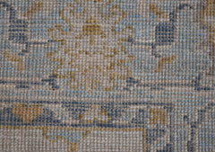 A handwoven transitional Oushak rug featuring a floral pattern in blue, yellow, and beige tones.