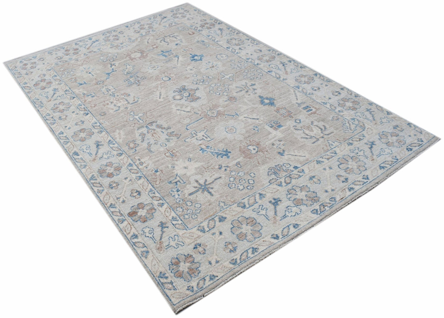 A handwoven transitional Oushak rug featuring a floral pattern in muted blue and beige tones.