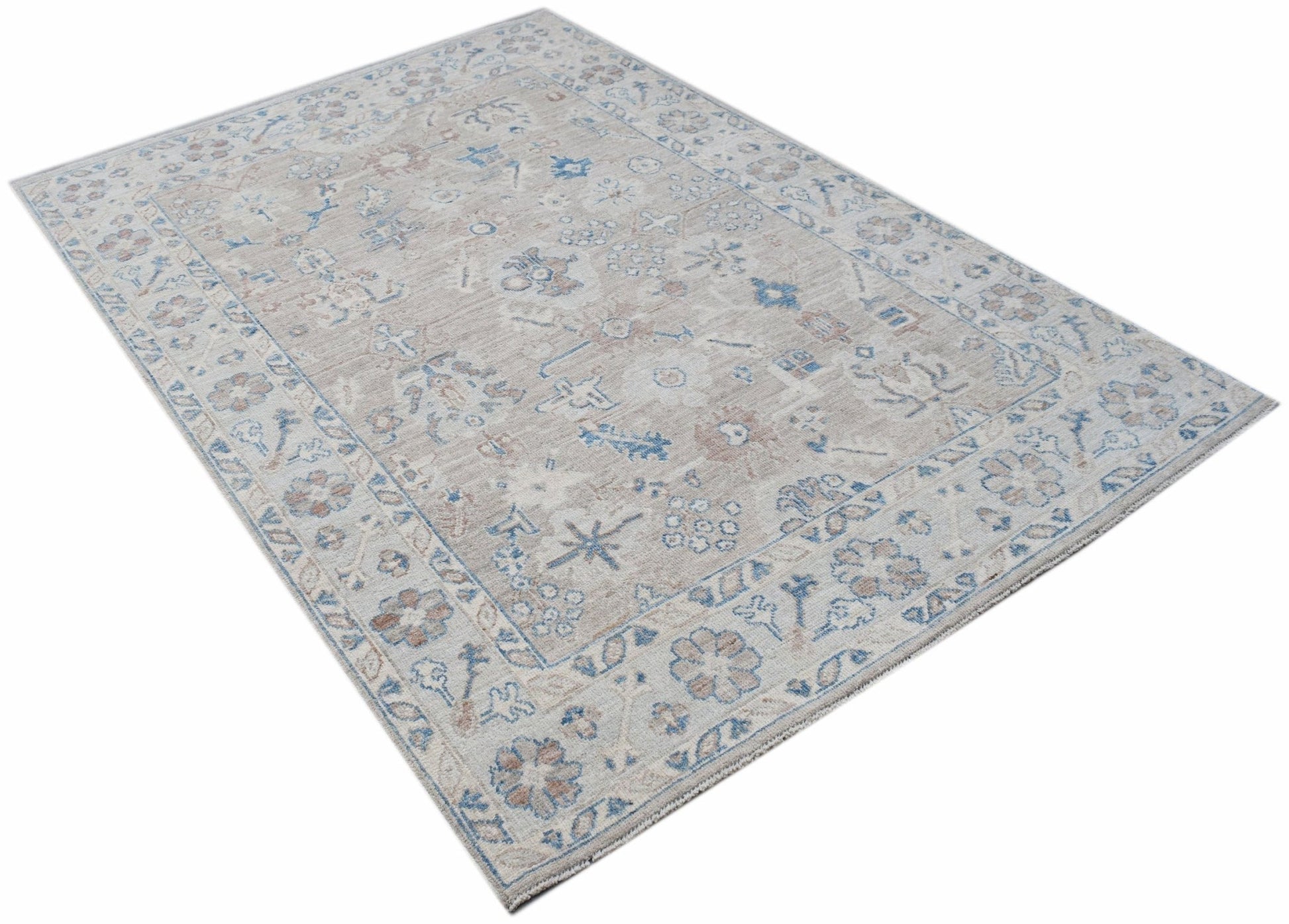 A handwoven transitional Oushak rug featuring a floral pattern in muted blue and beige tones.