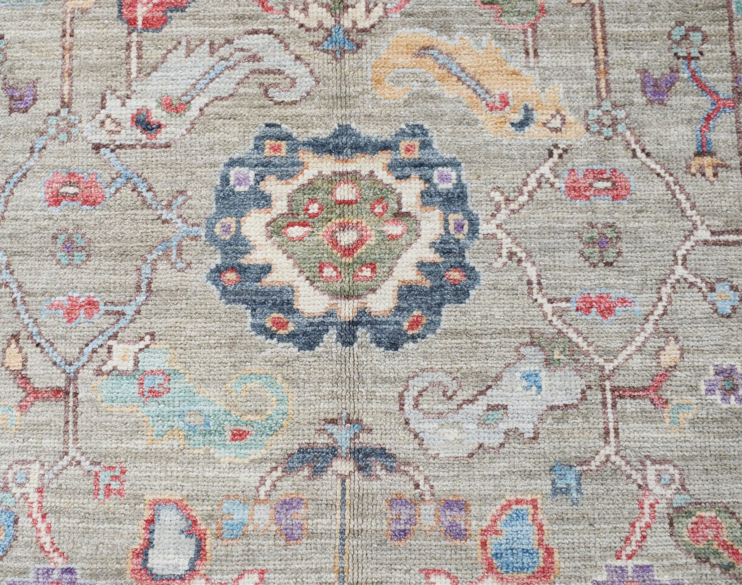 A handwoven transitional Oushak rug featuring a floral pattern in muted, contemporary colors.