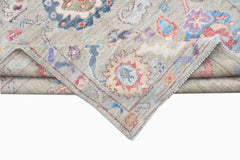 A handwoven transitional Oushak rug with a floral pattern in muted tones on a light grey background.