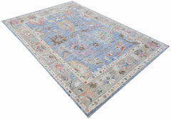 A handwoven transitional Oushak rug featuring a floral pattern in blue and neutral tones.