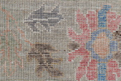 A close-up view of a handwoven Oushak rug featuring a floral pattern in muted tones.