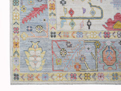 A handwoven transitional Oushak rug featuring a floral pattern in soft blue and neutral tones.
