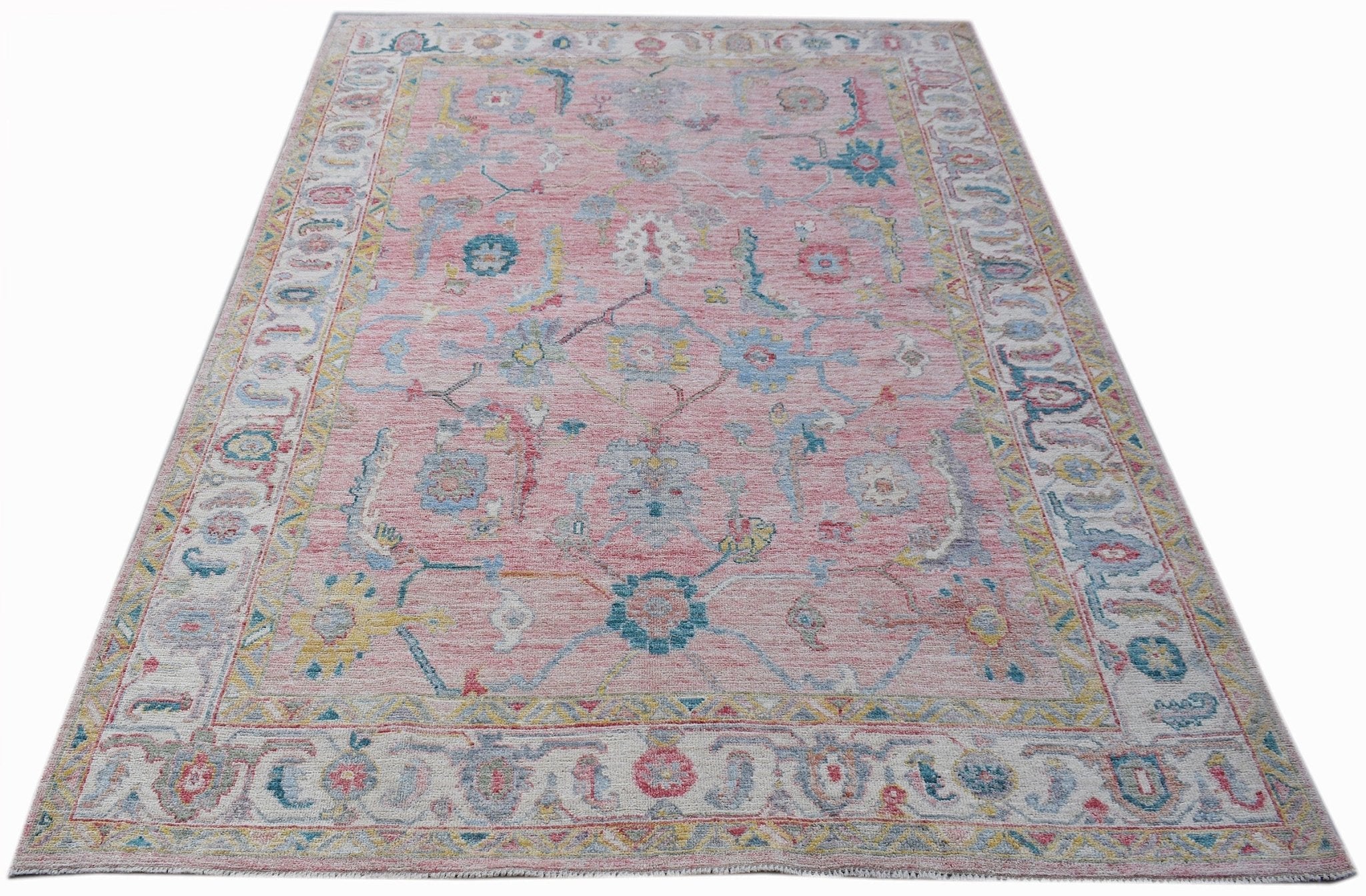A handwoven transitional Oushak rug featuring a floral pattern in pink, blue, and yellow tones.