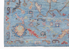 A handwoven transitional Oushak rug featuring a floral pattern in blue and multi-colored tones.