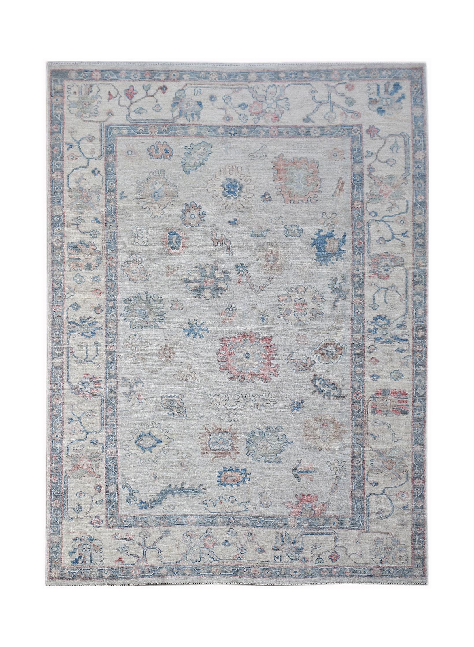 A handwoven transitional Oushak rug featuring a floral pattern in muted blue and pink tones.