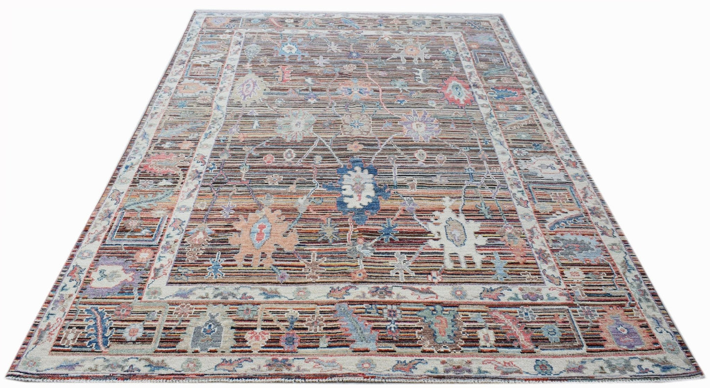 A handwoven transitional Oushak rug featuring a floral pattern in muted, multi-colored tones.