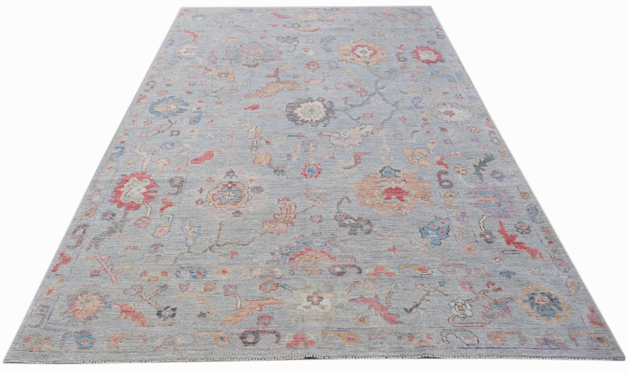 A handwoven transitional Oushak rug featuring a floral pattern in soft, muted colors.