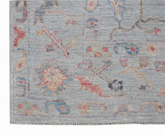 A handwoven transitional Oushak rug featuring a light blue field with colorful floral motifs.