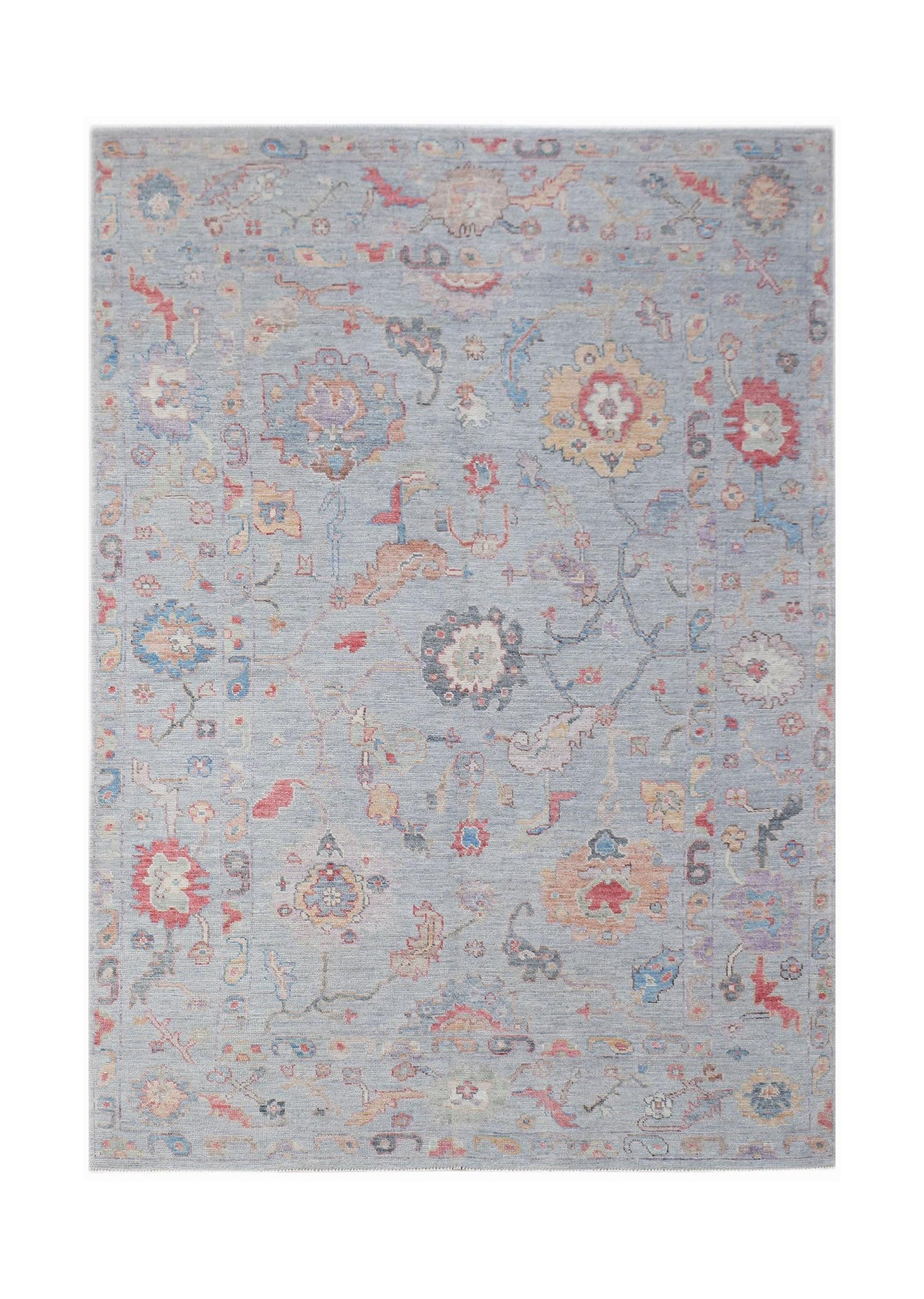 A handwoven transitional Oushak rug featuring a floral pattern in soft blue and multi-colored tones.