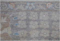 A handwoven transitional Oushak rug featuring a floral pattern in soft grey, blue, and tan tones.
