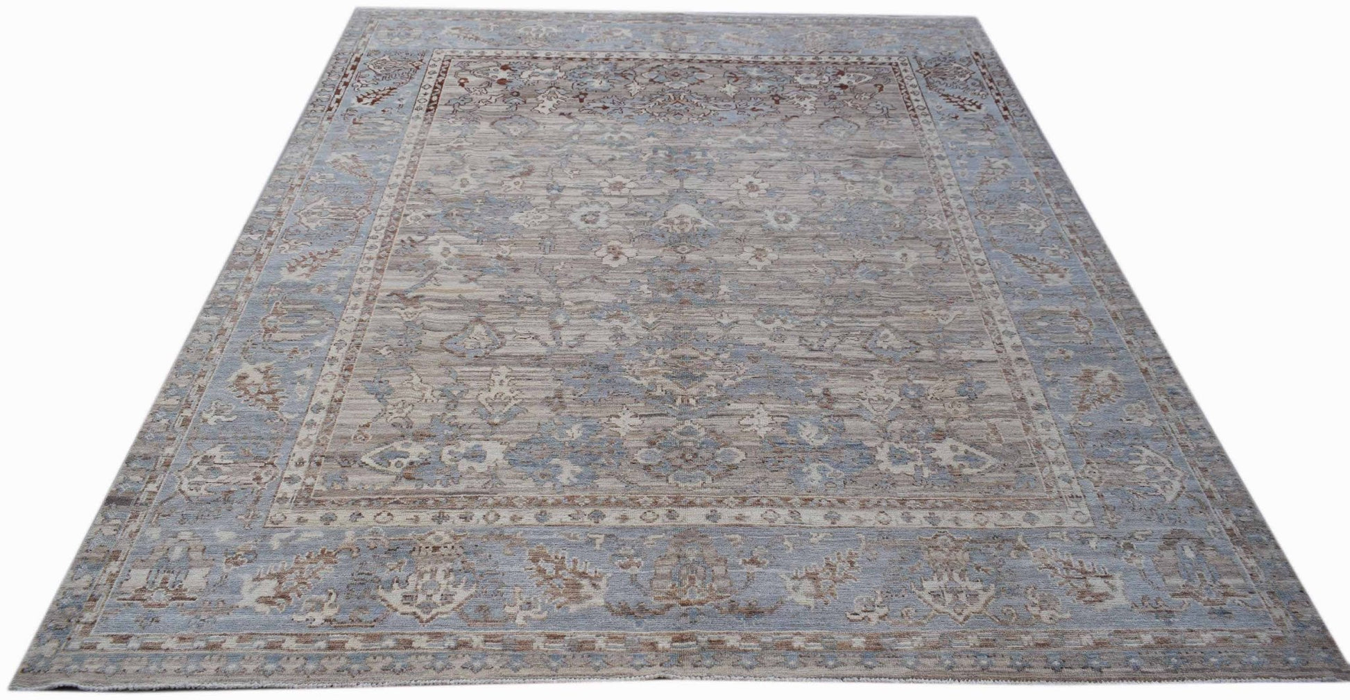 A handmade transitional Oushak rug featuring a soft blue and beige floral pattern.