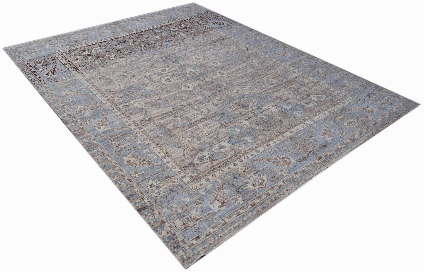 A rectangular transitional Oushak rug featuring a faded blue and beige floral pattern.