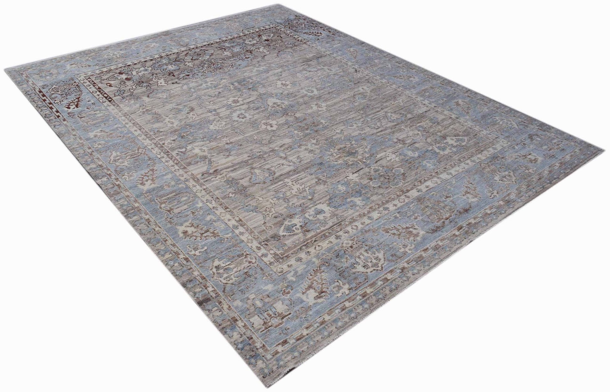 A rectangular transitional Oushak rug featuring a faded blue and beige floral pattern.