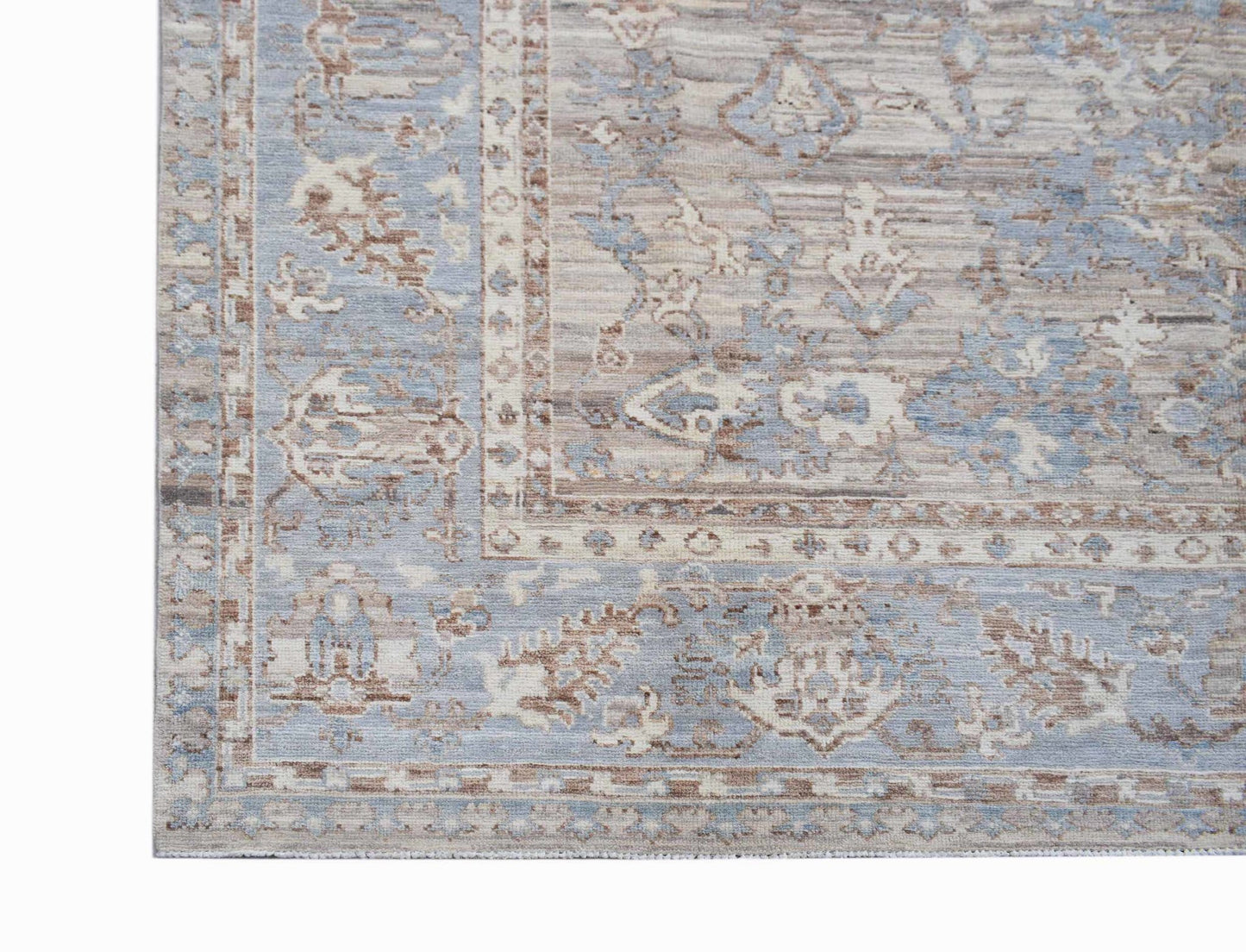 A transitional Oushak rug featuring a faded floral pattern in shades of blue, beige, and brown.