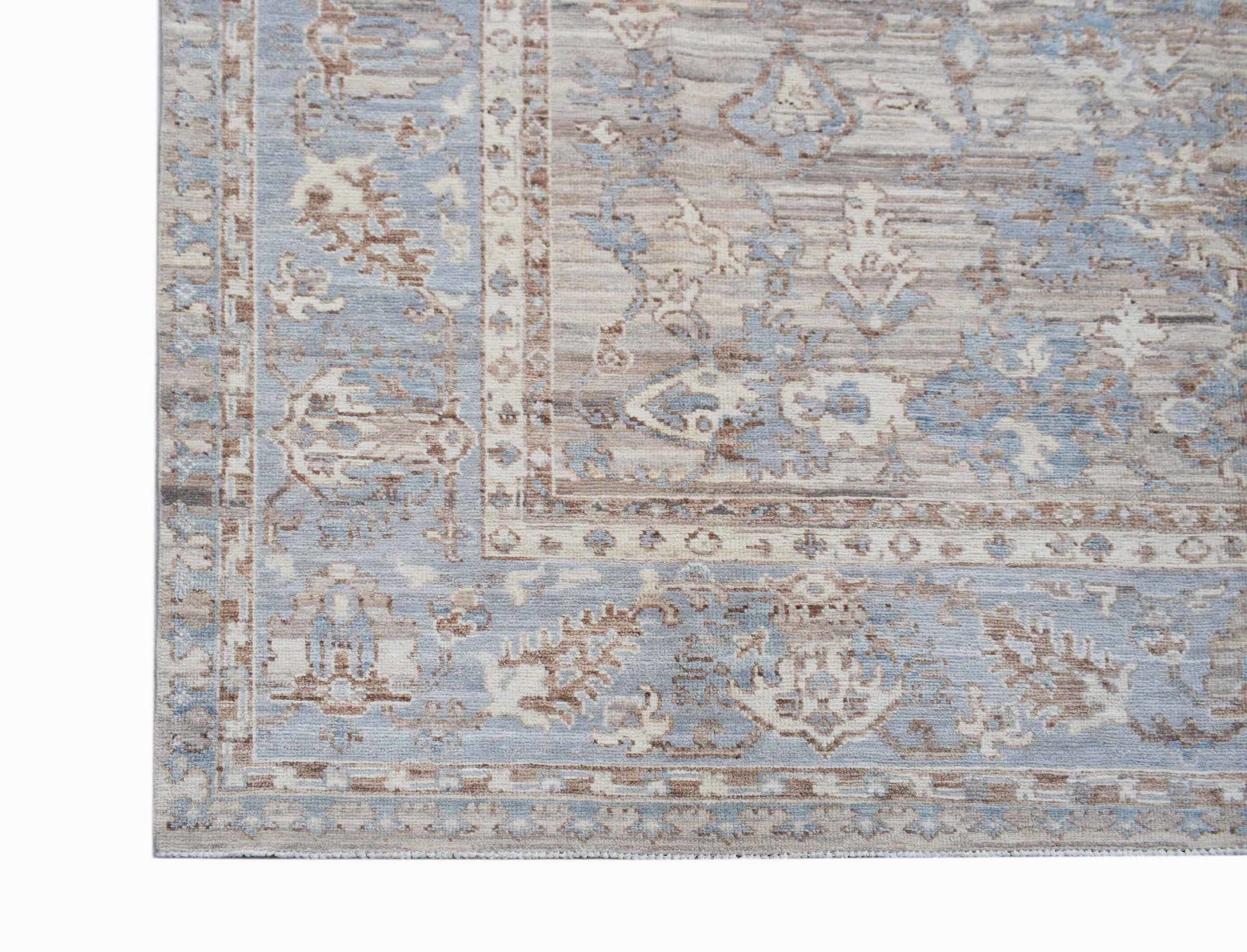 A transitional Oushak rug featuring a faded floral pattern in shades of blue, beige, and brown.