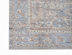 A transitional Oushak rug featuring a faded floral pattern in shades of blue, beige, and brown.