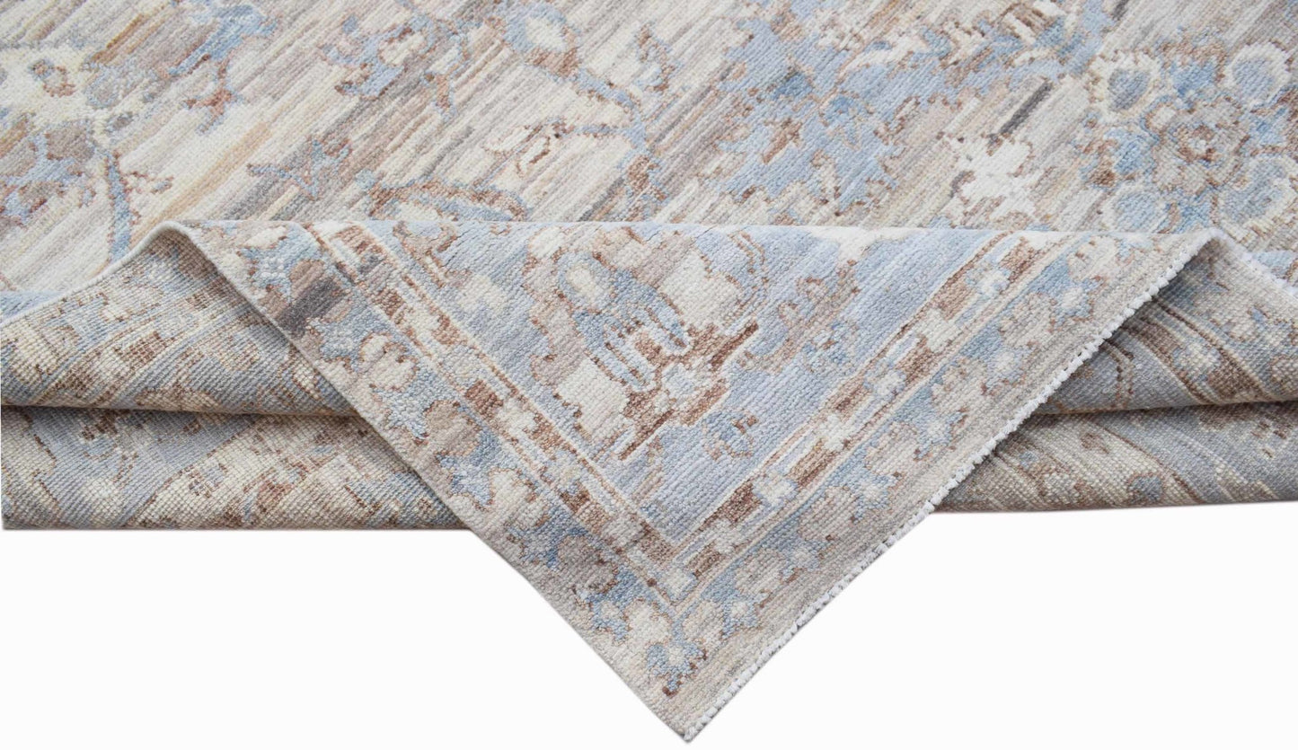 A handwoven transitional Oushak rug featuring a distressed pattern in shades of blue and beige.